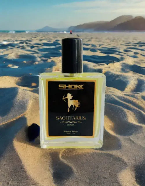 Shok Sagittarius perfume bottle on a sandy beach with mountains in the background

